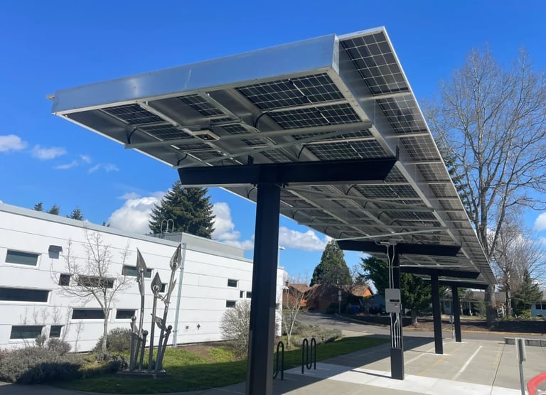 Solar panel carport structure in parking area with modern building and bare trees under clear blue sky